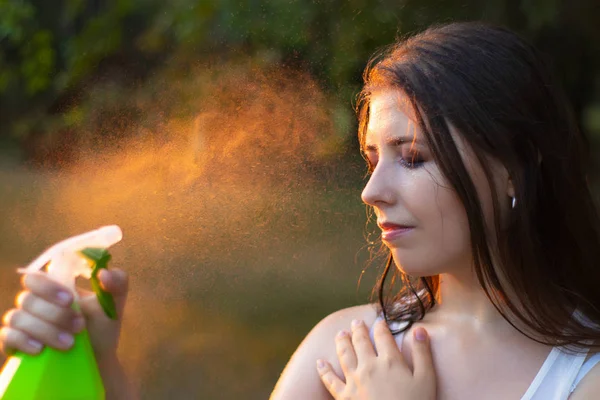 Young woman spraying water on herself from a spray bottle, close-up. — ストック写真