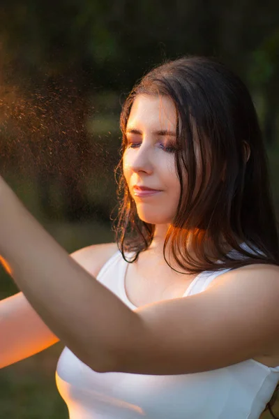 Mujer joven rociando agua sobre sí misma de una botella de spray, primer plano . — Foto de Stock