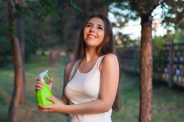 Mujer joven rociando agua sobre sí misma de una botella de spray en un parque de verano . — Foto de Stock