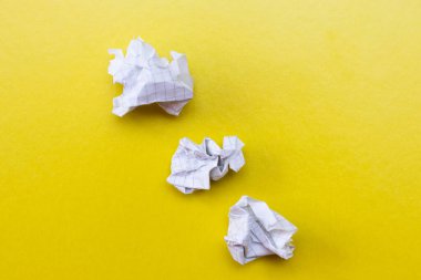 Lumps of crumpled paper on a yellow background.