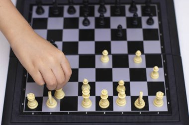 Çocuk eli satranç tahtasındaki bir taşı oynatıyor. Satranç oynamayı öğrenmek, mantığın gelişimi, bir fotoğraf..