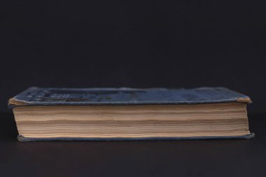 Siyah arka planda kalın bir kitap. Kitap yatay pozisyonda, bir fotoğraf..