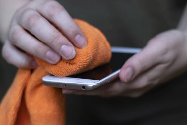 Eldivenli eller akıllı telefonun yüzeyini siler. Bir salgın sırasında ev aletlerinin dezenfekte edilmesi, telefon yoluyla virüs bulaşması