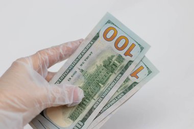 Tek kullanımlık koruyucu eldivendeki bir el dolar tutar. Koronavirüs salgını sırasında alınan önlemler, fotoğraf...