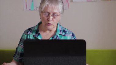Dizüstü bilgisayardaki yaşlı kadın. Karantina sırasında internette konuşan bir kadın.