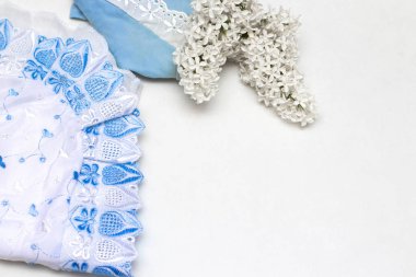 Beyaz bir leylak dalı ve beyaz arka planda yeni doğan bebek için eşyalar. Metnin altına yerleştir, boşluğu kopyala