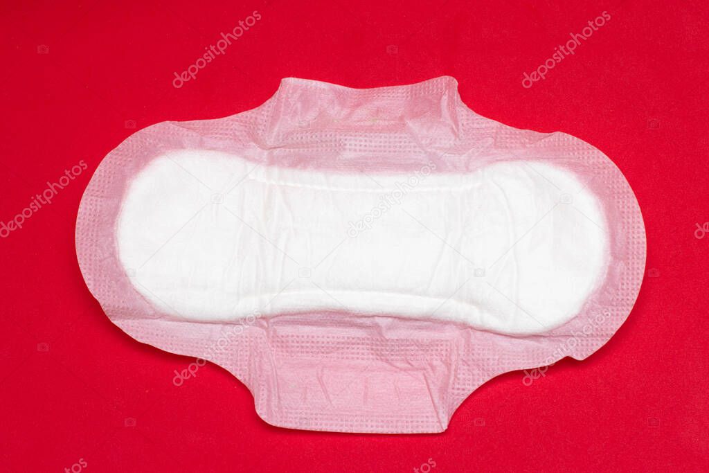 Feminine sanitary pad on a red background. Hygiene during menstruation
