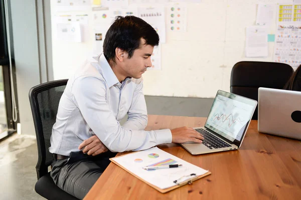 Yakışıklı işadamı oturmak sandalye ofis, iş kavramı içinde laptop ile çalışma
