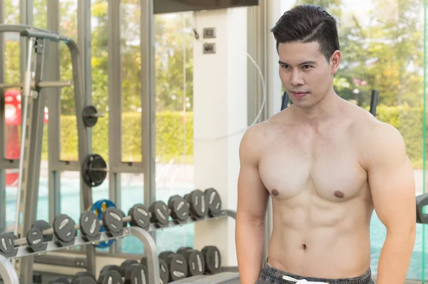 Montrer les muscles du corps du bel homme dans la salle de gym ou centre de remise en forme — Photo