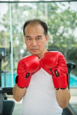 Yaşlı adam giyen kırmızı boks fitness egzersiz eldiven Merkezi ve kamera, savaşmaya hazır bakmak