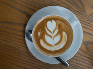 Kalp desenli ahşap arka plan, Sıcak karamel latte üzerinde beyaz bir fincan kahve