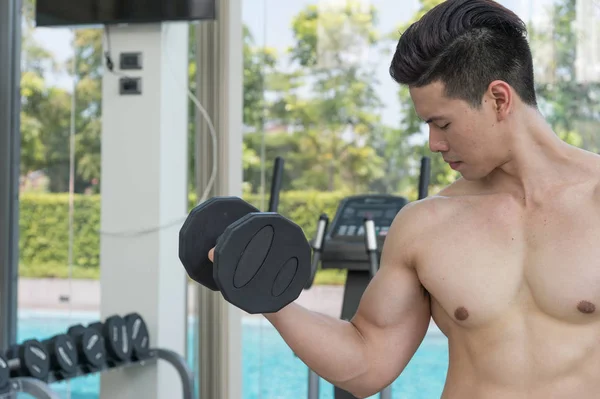 Homem do esporte está trabalhando com halteres, exercitando-se no ginásio ou fitness . — Fotografia de Stock