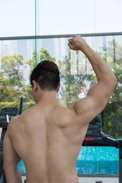 Homem bonito mostrar corpo muscular no ginásio ou centro de fitness, conceito saudável — Fotografia de Stock