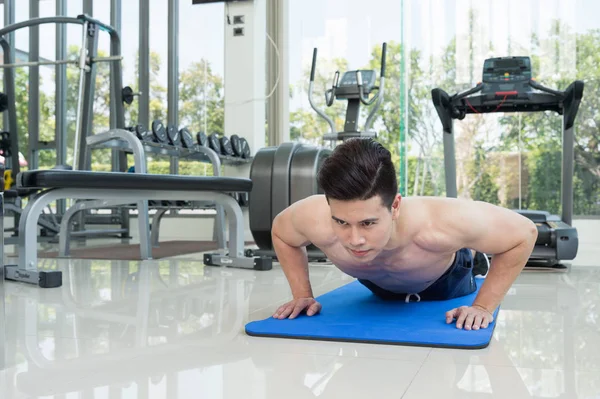 handsome man fitness exercising by doing push ups as part of bodybuilding training in the fitness center or gym, sport and health concept.