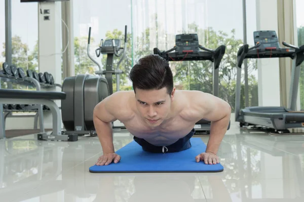 handsome man fitness exercising by doing push ups as part of bodybuilding training in the fitness center or gym, sport and health concept.