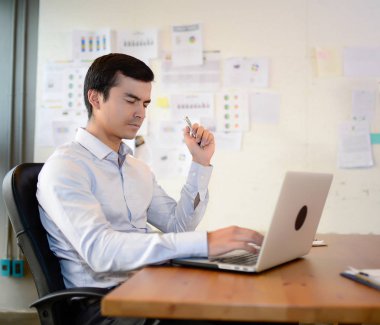 Yakışıklı iş adamı sandalyeye otur ve iş laptop ile ofiste başarılı konsept