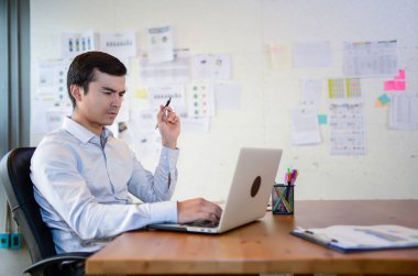 Yakışıklı iş adamı sandalyeye otur ve iş laptop ile ofiste başarılı konsept