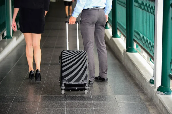 Hombre de negocios y mujer de negocios caminan juntos con equipaje negro, viajes de negocios — Foto de Stock