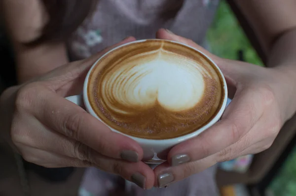 Женщина держит чашку кофе, сердечный узор, горячий латте — стоковое фото