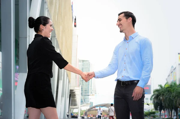 Hombre de negocios y mujer de negocios estrechando la mano sonrisa para el acuerdo de éxito en el lugar al aire libre — Foto de Stock