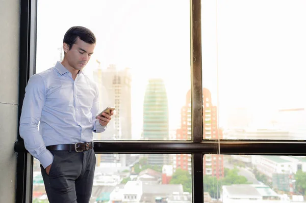 Hombre de negocios guapo utilizar el teléfono inteligente responder a los mensajes . — Foto de Stock