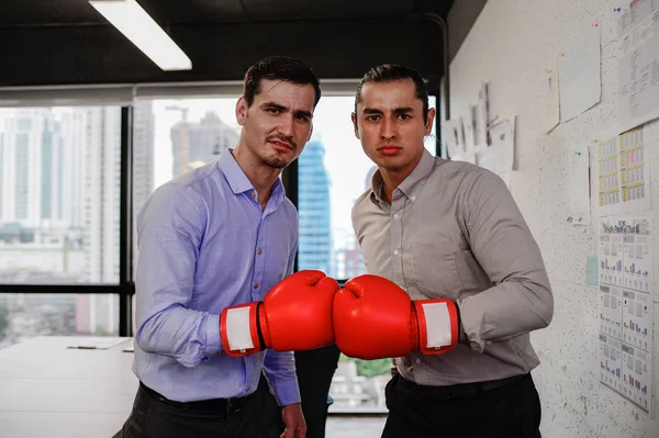 Zwei Geschäftsleute schauen Kamera mit Boxhandschuhen im Büro — Stockfoto