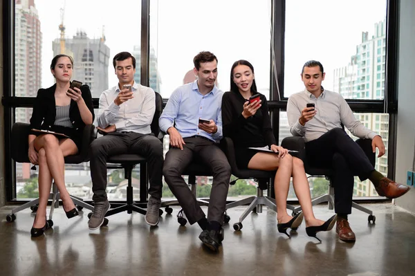 Tres hombres de negocios y dos mujeres de negocios relajarse sentarse en la silla y mantener el teléfono en la ventana en la oficina — Foto de Stock