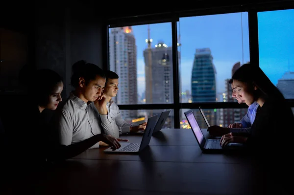 Equipe de negócios trabalhando com horas extras do computador à noite e pouca luz — Fotografia de Stock