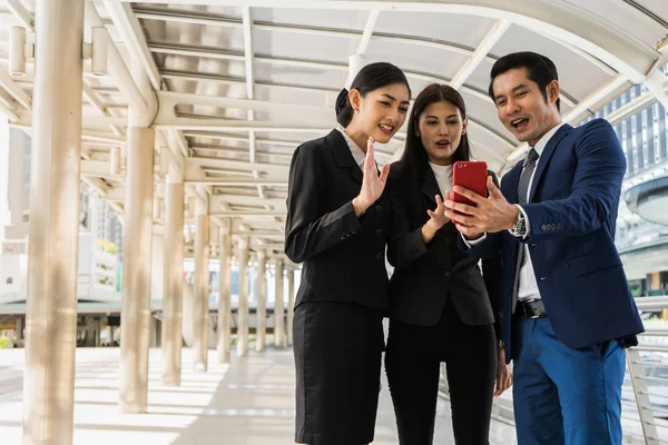 Asiatisk forretningsmann og forretningskvinne som gjør konferansesamtale med noen på mobil – stockfoto