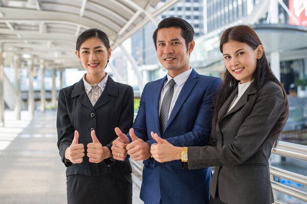 бизнесмен и деловая женщина улыбаются и показывают большой палец вверх двумя руками
