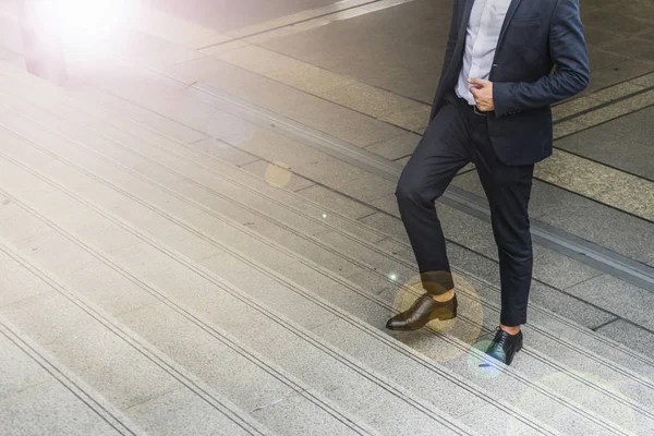 Piernas de hombre de negocios usan traje negro caminando escalando escaleras en la ciudad moderna, negocio crecer y concepto de éxito, concepto de ambiciones — Foto de Stock