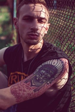 çitin oturan dövmeli adam 