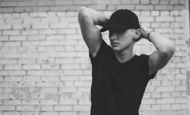 genç adam elleriyle bir tuğla duvar arka plan, siyah ve beyaz başının arkasında poz bir kap içinde