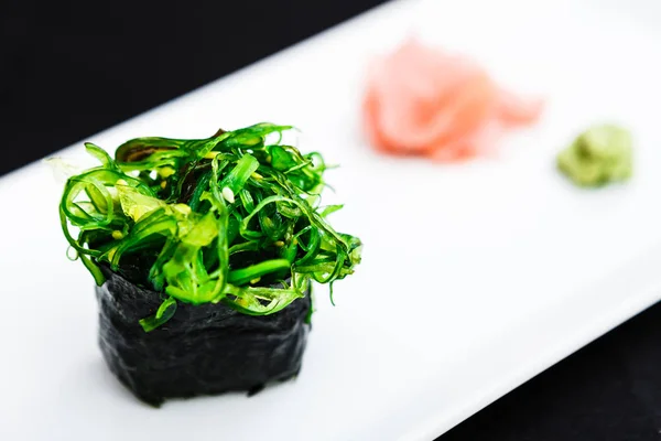 Sushi with seaweed served on a plate with ginger and wasabi