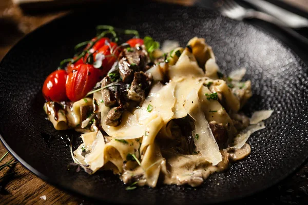 Black Angus Pasta servert i en svart bolle på restaurant – stockfoto