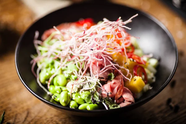 Poke with beef served in a black bowl in restaurant — Stock Photo, Image