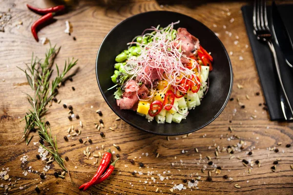 Poke with beef served in a black bowl in restaurant — Stock Photo, Image