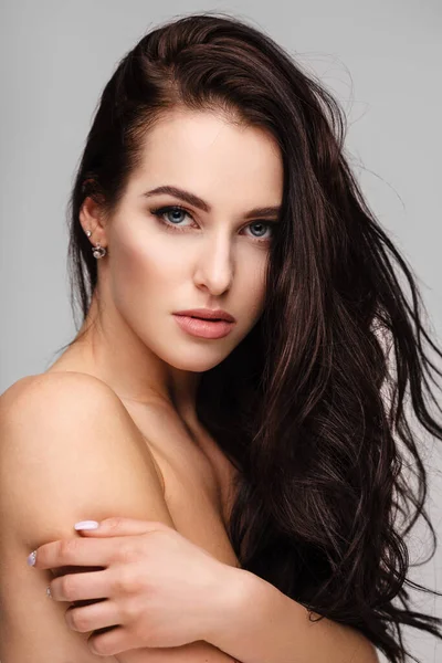 Portrait of a young lady with beautiful brunette hair on grey — Stockfoto