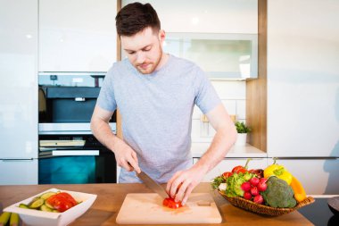 Genç ve mutlu bir adam evde yemek hazırlıyor.