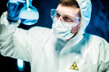 Corona virüsü konsepti. Erkek doktor cam şişeyi inceliyor.