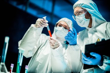 Corona virüsü konsepti. İki doktor test tüpünü inceliyor.