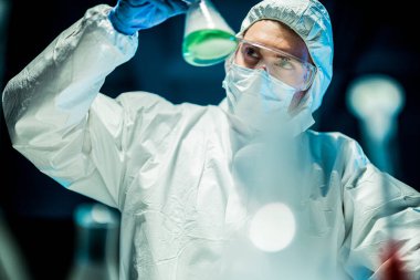 Corona virüsü konsepti. Erkek doktor cam şişeyi inceliyor.