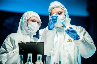 Corona virüsü konsepti. İki doktor test tüpünü inceliyor.