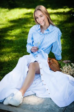 Parkta piknikte dinlenen mutlu genç bir kadının portresi.