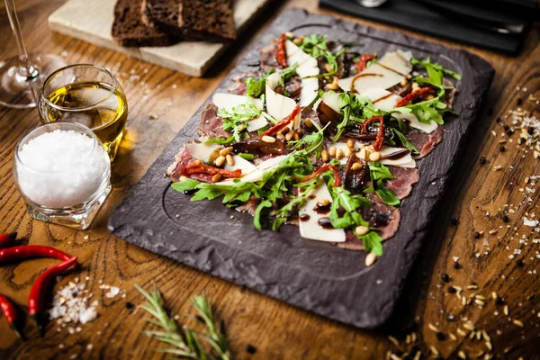 Siyah taş tahtada sığır eti carpaccio. Lezzetli sağlıklı İtalyan geleneksel antipasti aperatifleri modern gurme restoranında öğle yemeği olarak bir masada servis edilir.. — Stok fotoğraf