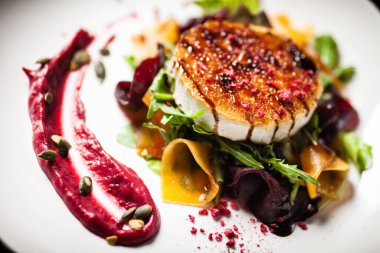 Izgara keçi peynirli salata turşulu pancar ve kabak, kızılcık reçeli, beyaz tabakta kabak çekirdeği. Lezzetli sağlıklı Akdeniz geleneksel vejetaryen yemekleri öğle yemeği için bir masada servis edilir.