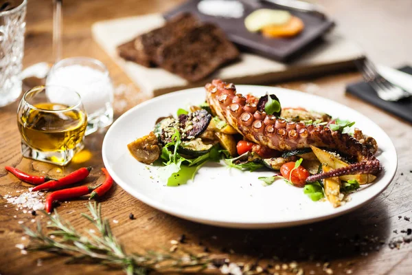 Теплый салат из осьминога с жареными овощами и соусом дзи на белой тарелке. Вкусные здоровые средиземноморские традиционные морепродукты крупным планом подаются на стол на обед . — стоковое фото