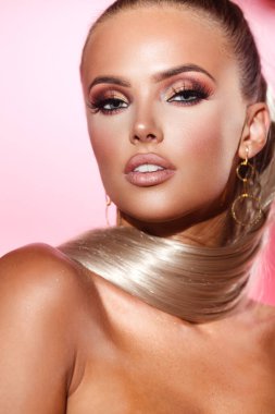 Cilt bakımı, makyaj ve kozmetik konsepti. Pembe arka planda büyüleyici makyajı olan güzel bir kadının portresi.