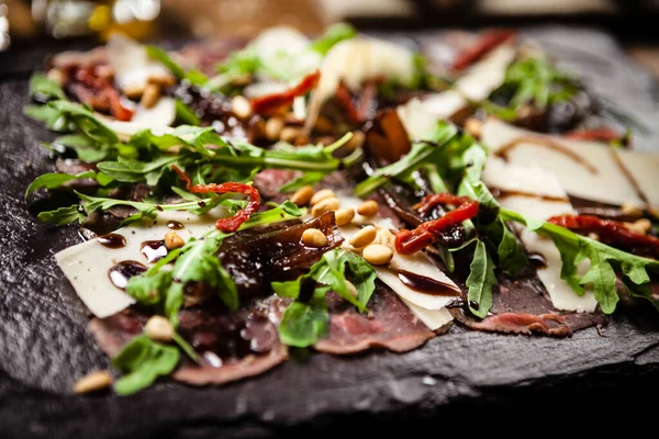 Carpaccio di manzo servito su una tavola. Deliziosi antipasti tradizionali italiani primi piani serviti a pranzo con vino nel moderno ristorante gourmet . — Foto Stock