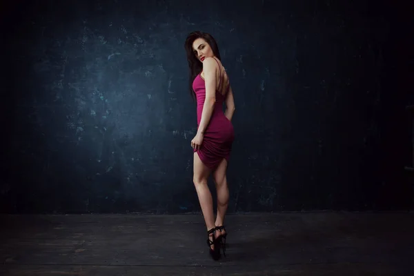 Koyu arka plan üzerinde duruyor poz Kırmızı elbiseli çekici şık moda modeli. Sonbahar moda. Vogue stili.
